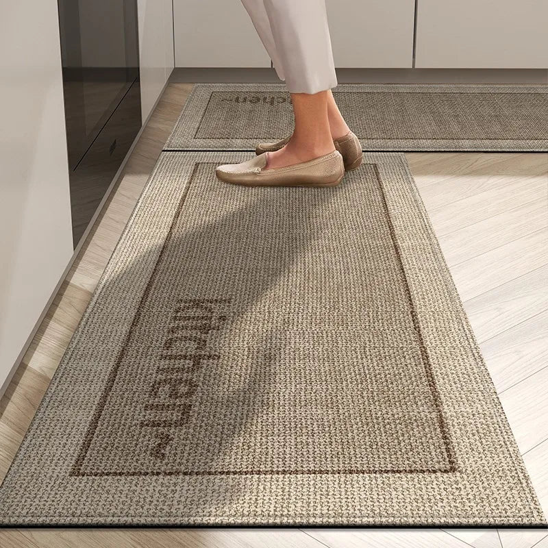 Gros plan sur un tapis motif grillage beige et marron, sur lequel se trouve un pied chaussé d'une paire de mocassins.
