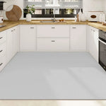 Cuisine minimaliste avec des meubles blancs, un comptoir en bois clair et des accents de plantes vertes, reflétant un design épuré et fonctionnel.