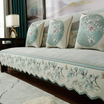 Un canapé confortable et élégant avec des coussins ornés de motifs floraux délicats dans des teintes douces de vert et de rose.