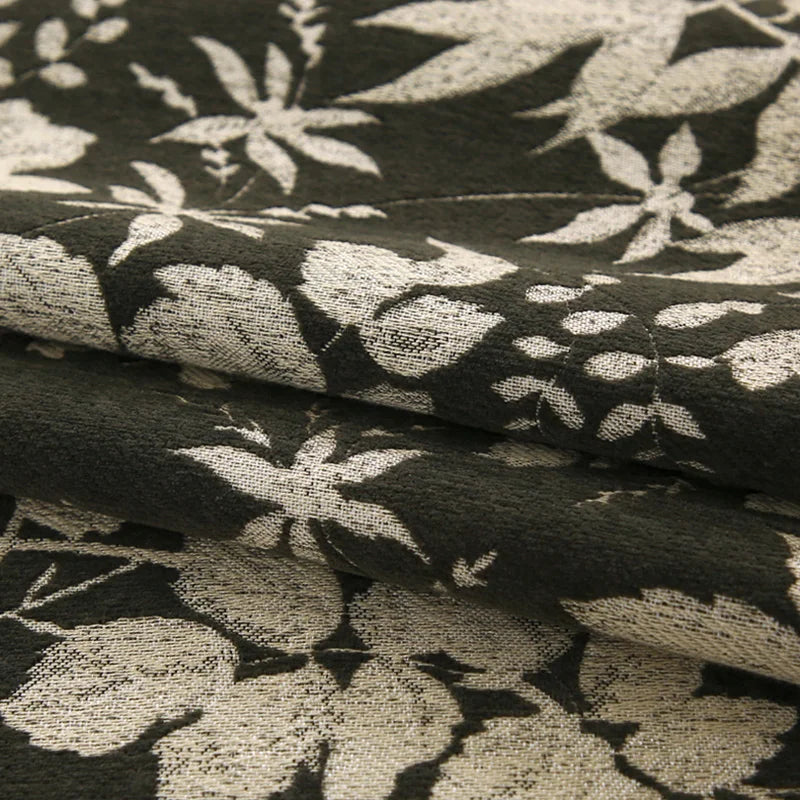 Un motif floral décoratif dans des tons de gris crée une texture élégante et sophistiquée sur ce tissu.
