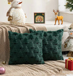 Coussin décoratif vert à motifs d'arbres de Noël, entouré de jouets et de décorations saisonnières sur un canapé douillet.
