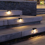 Lampe solaire murale orange éclairant des marches de jardin
