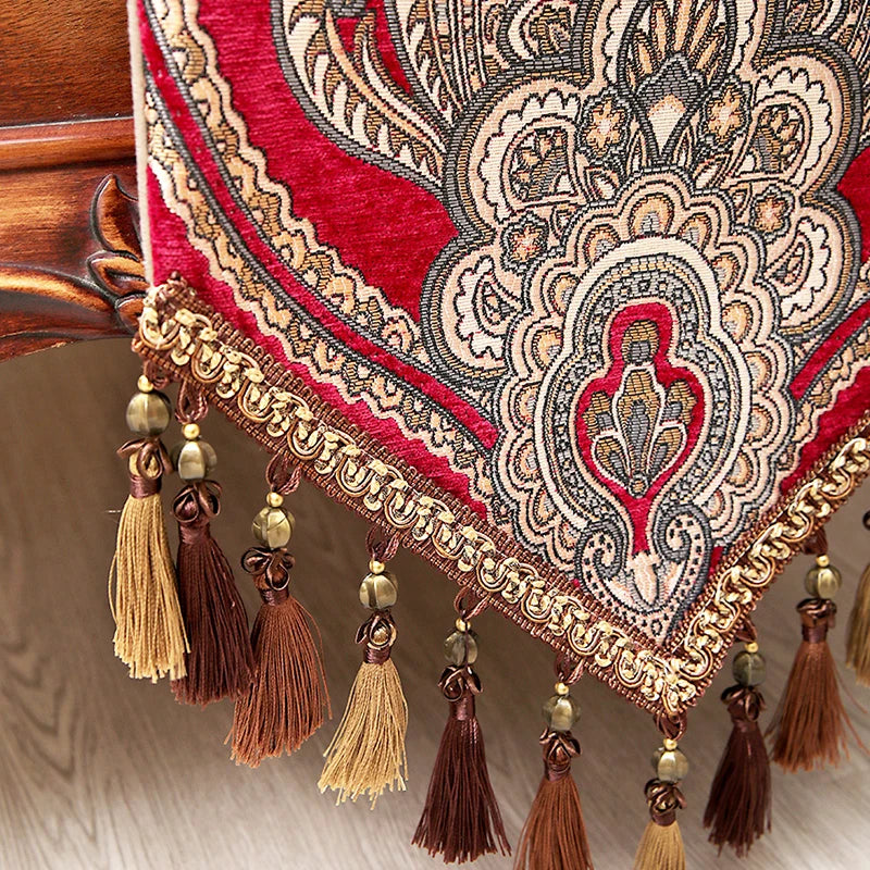 Un magnifique châle décoratif aux riches motifs floraux et ornements dorés, rehaussé de franges et de pompons élégants.