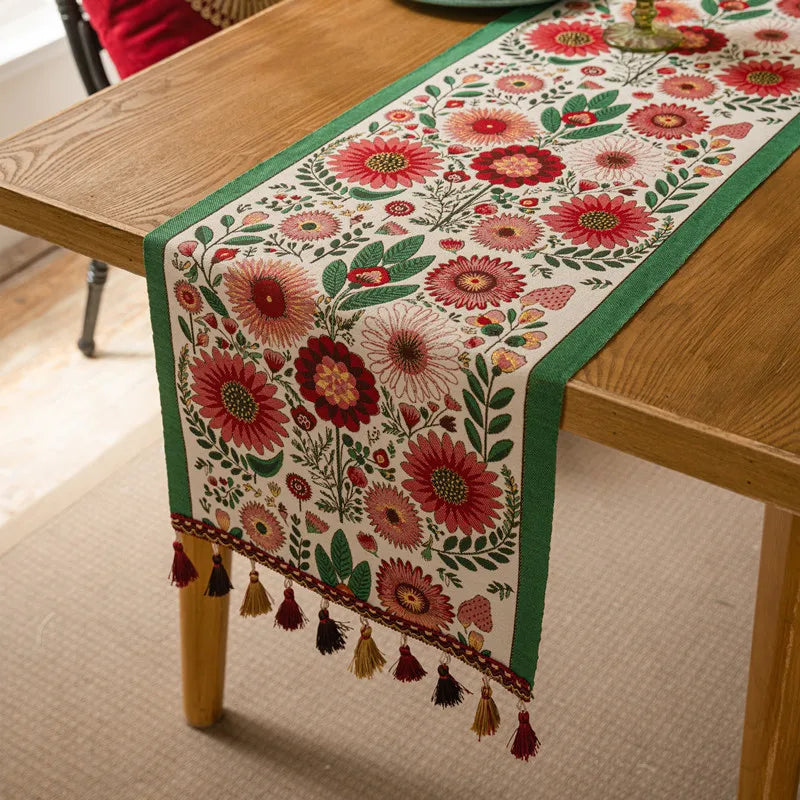 Une nappe de table ornée de belles fleurs rouges et vertes avec des glands aux couleurs chaudes.
