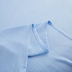 Une couverture tissée bleu pâle avec un motif texturé et des plis ondulants.