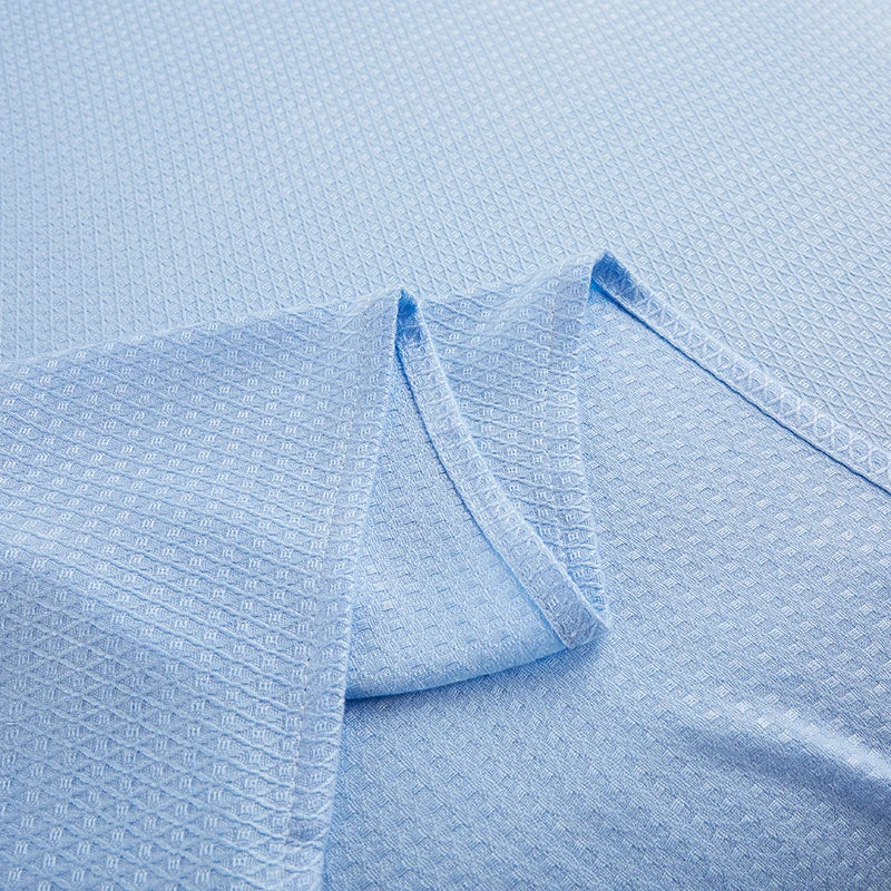 Une couverture tissée bleu pâle avec un motif texturé et des plis ondulants.