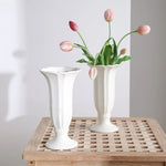 Un arrangement délicat de tulipes roses dans des vases blancs sur une table en bois, créant une ambiance apaisante et élégante.