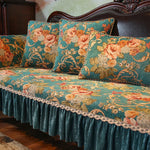 Un canapé antique aux motifs floraux élégants et colorés dans des tons de vert et de orange, avec des coussins assortis, créant une atmosphère chaleureuse et luxueuse.