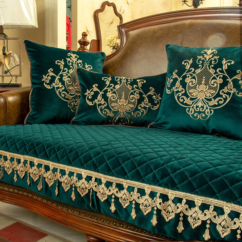 Des coussins de velours vert émeraude ornés de motifs dorés raffinés, avec une magnifique couverture matelassée au même motif, créent une atmosphère luxueuse et chaleureuse dans cette élégante pièce d'ameublement.