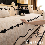 Une belle chambre élégante ornée de motifs de papillons et de cœurs noirs sur une couverture beige, avec des coussins assortis et une tasse décorative, créant une atmosphère chaleureuse et sophistiquée.