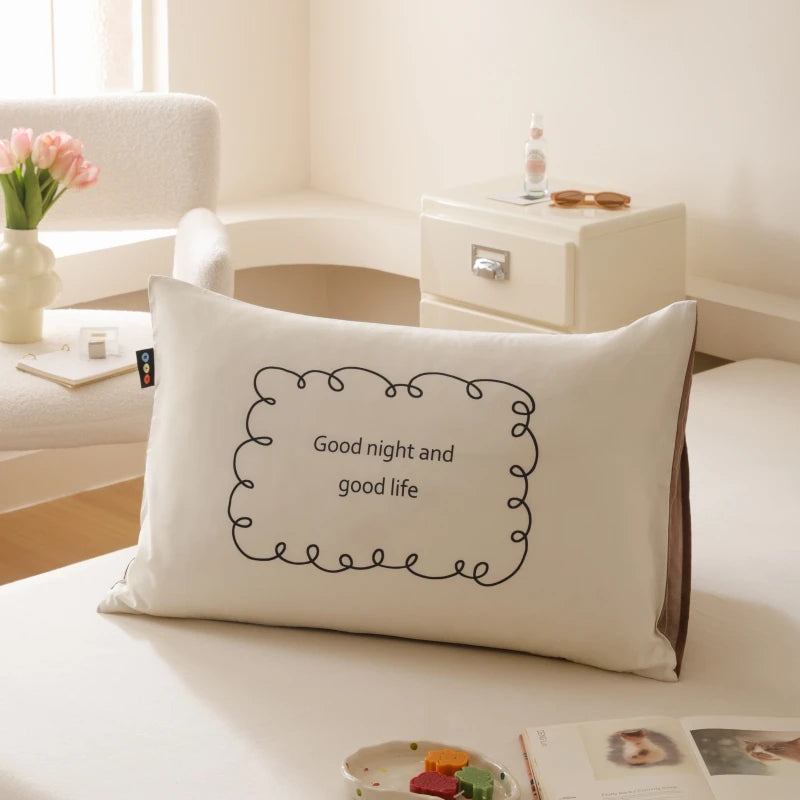 Coussin décoratif blanc avec l'inscription « Bonne nuit et bonne vie » dans un cadre ornemental.