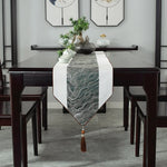 L'image montre une élégante table à manger en bois foncé avec un chemin de table décoratif orné de motifs graphiques, accompagnée de plantes vertes et d'accessoires dans un style épuré et moderne.