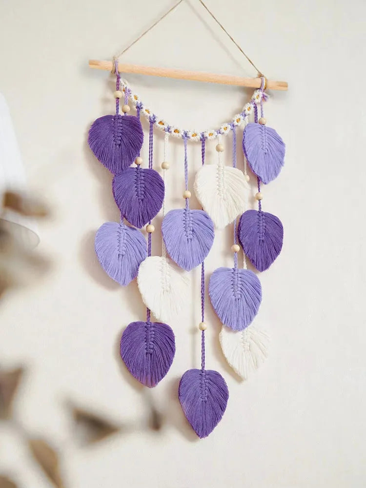 Un joli mobile fait de feuilles macramé violettes et blanches, suspendu à un cadre en bois, crée une décoration murale apaisante et élégante.