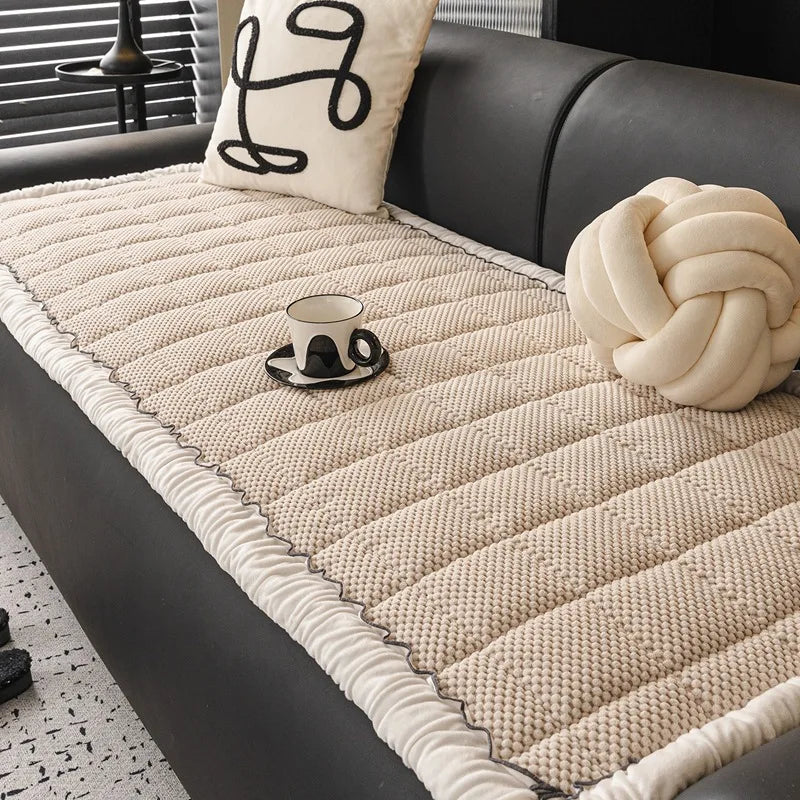 Couvre-lit texturé beige avec coussin décoratif et accessoire de décoration sur un canapé sombre.