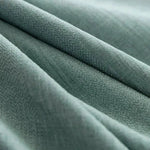 Tissu vert doux en gros plan montrant une texture délicate et élégante, idéal pour la décoration intérieure ou la confection de vêtements raffinés.