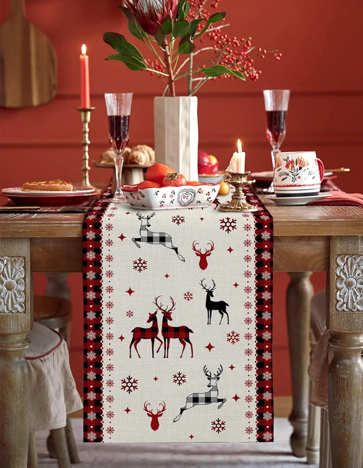 Cette magnifique table de fête est décorée de motifs traditionnels de Noël, avec des cerfs et des flocons de neige imprimés sur un chemin de table blanc, créant une ambiance chaleureuse et festive.