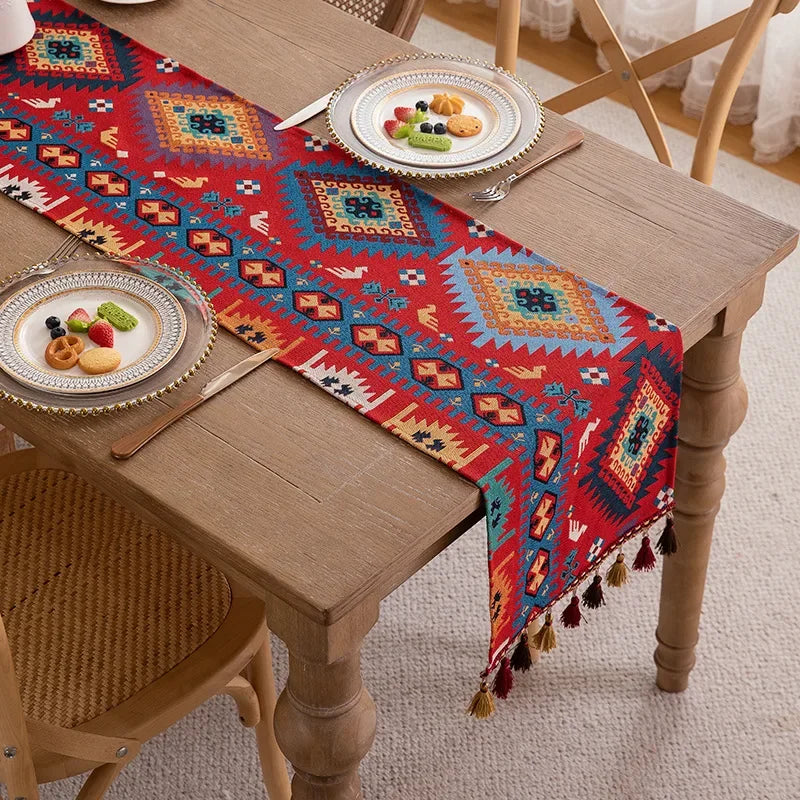 Un chemin de table aux motifs ethniques vifs et colorés, avec des formes et des couleurs qui contrastent agréablement avec le mobilier en bois clair.