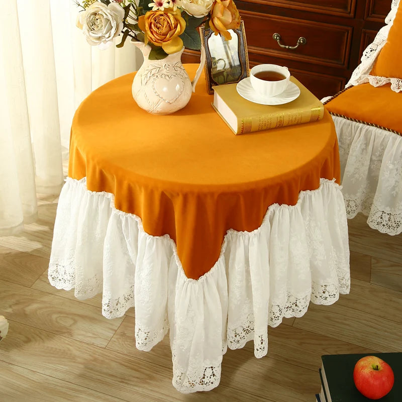 Cette table ronde chaleureuse est ornée d'une nappe orange aux bords blancs et dentellés, d'un vase de fleurs, d'une tasse de thé et d'un livre, créant une ambiance accueillante et confortable.