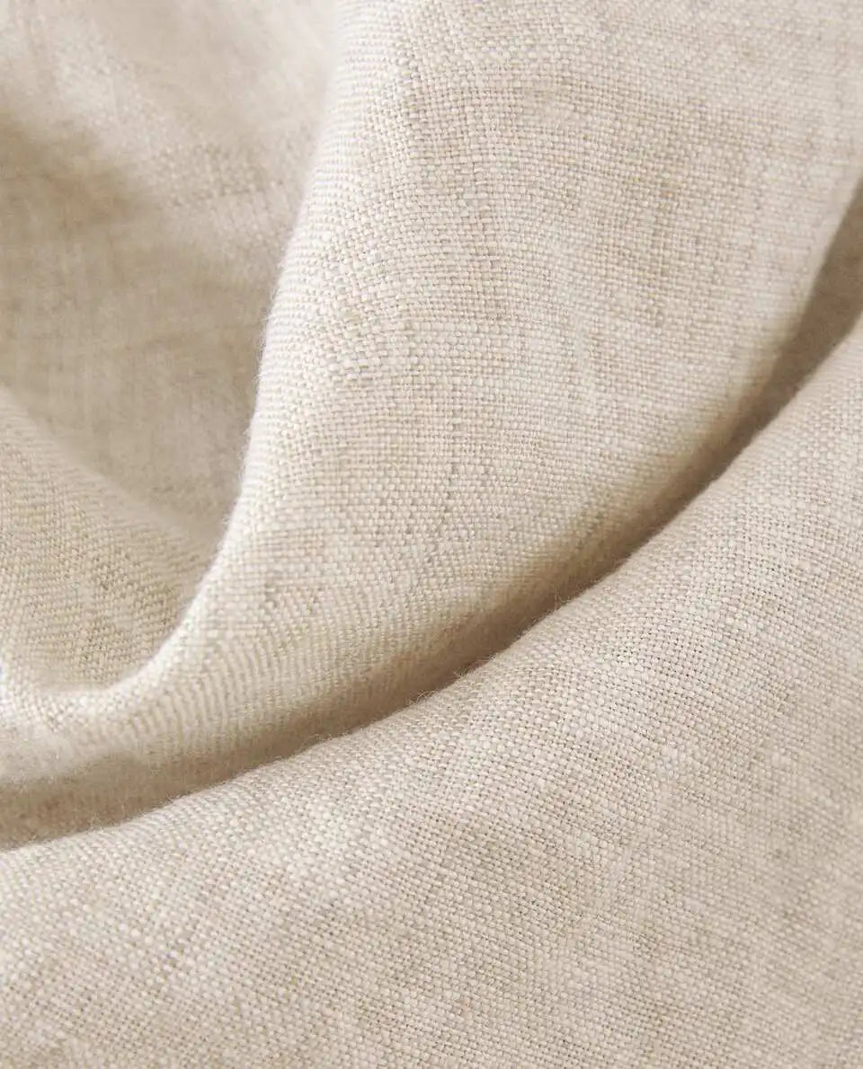 Texture douce et naturelle d'un tissu beige aux reflets nuancés, offrant une sensation de confort et de qualité.