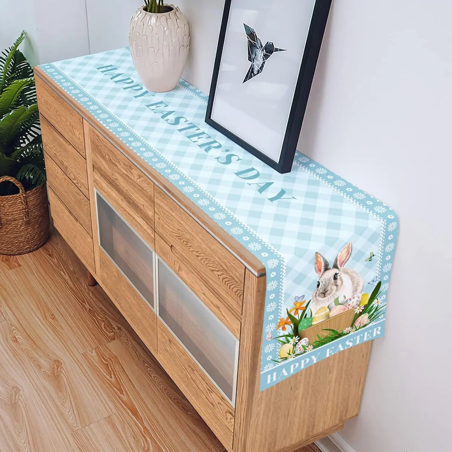 Un meuble en bois avec une jolie nappe à motifs de lapins et de fleurs de Pâques.