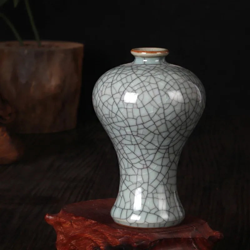 Une délicate vase antique en céramique aux motifs de craquelures subtils, posé sur un support brun foncé, créant une ambiance mystérieuse et élégante.