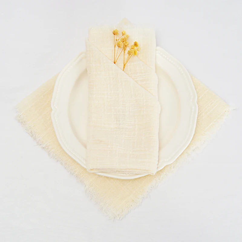 Une assiette et une serviette blanches avec quelques fleurs jaunes posées dessus sur un fond blanc.