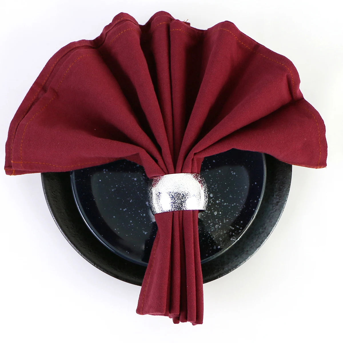 Serviette pliée en accordéon de couleur rouge foncé posée sur un fond noir.