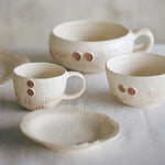 Série de tasses en céramique blanche aux détails marrons décorés.