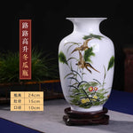 Vase en porcelaine blanche décoré de motifs de plantes et d'un oiseau en vol, sur un support en bois.