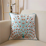 Un coussin avec un motif coloré de paon en plumes rouges et vertes sur un fond blanc, offrant une touche décorative apaisante à l'intérieur.