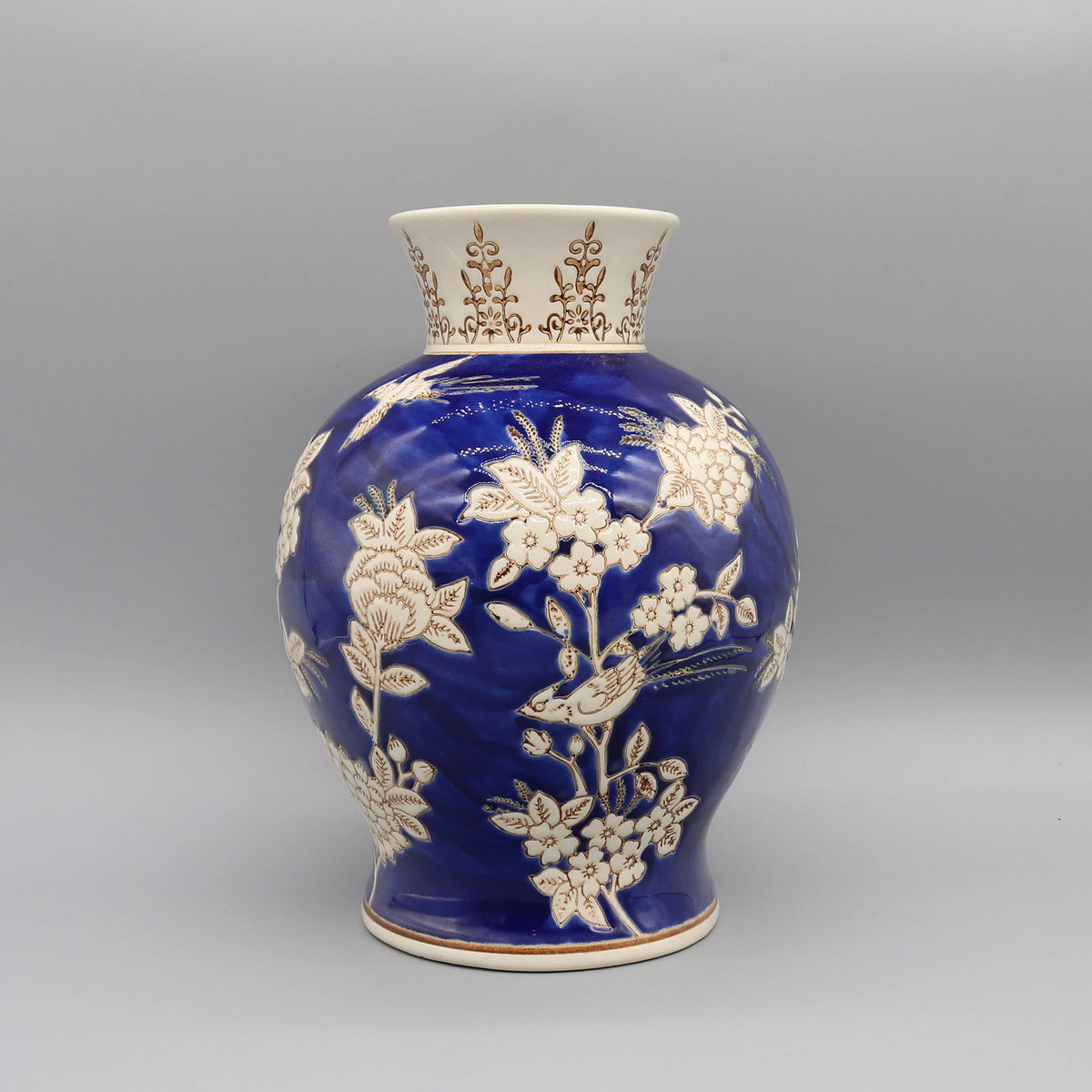 Vase en céramique bleu avec motifs floraux blancs et dorés, créant un contraste élégant et décoratif.