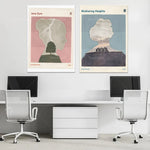 Deux affiches artistiques de littérature classique accrochées au-dessus d'un espace de travail moderne avec des bureaux et un meuble de rangement.