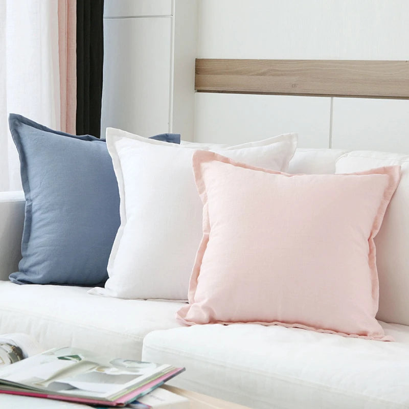 Un intérieur calme et épuré avec des coussins de couleurs douces et apaisantes posés sur un canapé blanc, créant une atmosphère chaleureuse et reposante.