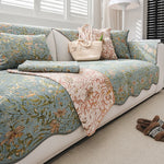 Ce canapé fleuri aux tons verts et roses, avec des motifs de fleurs et de feuillages, crée une ambiance chaleureuse et accueillante dans cette pièce ensoleillée.