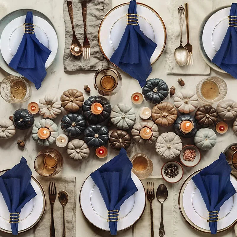 Une table élégante décorée de plats de porcelaine, de couverts dorés, de serviettes bleu marine et de nombreuses décorations florales en céramique, créant une ambiance chaleureuse et raffinée.