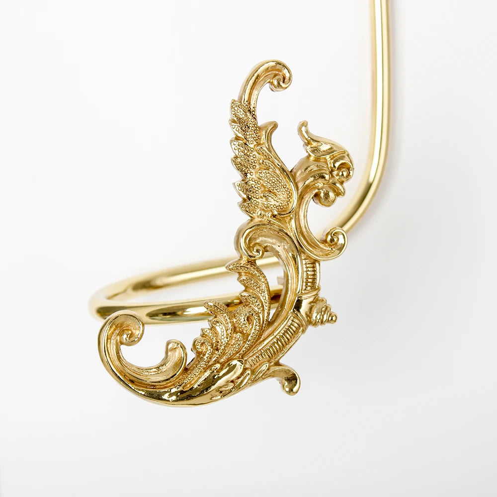 L'image montre un élégant ornement doré aux motifs floraux et décoratifs, avec des formes élégantes et des détails raffinés.