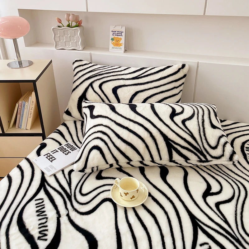 Une chambre moderne avec une couverture à motif zébré noir et blanc posée sur un lit, une lampe rose sur une table de chevet, et des décorations sur une étagère.