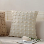 Coussin décoratif blanc moelleux avec motif texturé sur un canapé beige confortable.