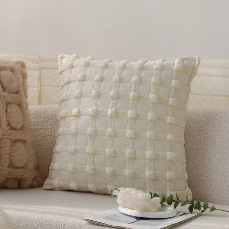 Coussin décoratif blanc moelleux avec motif texturé sur un canapé beige confortable.