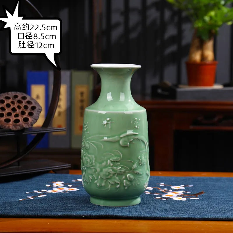 Un magnifique vase en céramique d'un vert pâle décoré d'un motif floral, posé sur une table avec d'autres objets décoratifs.