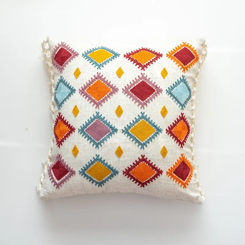 Coussin décoratif avec motif géométrique coloré sur fond blanc, créant un design vibrant et ethnique.