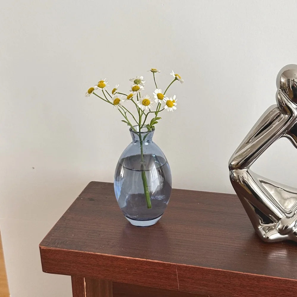 Collection de mini vases en verre de différentes couleurs sur une étagère