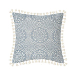 Coussin décoratif gris et blanc avec motifs floraux et pompons.