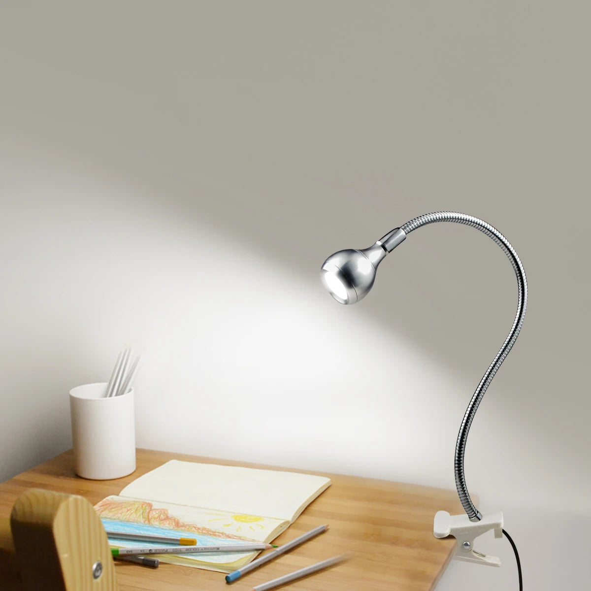 Lampe de lecture USB argentée éclairant un livre sur une table de chevet