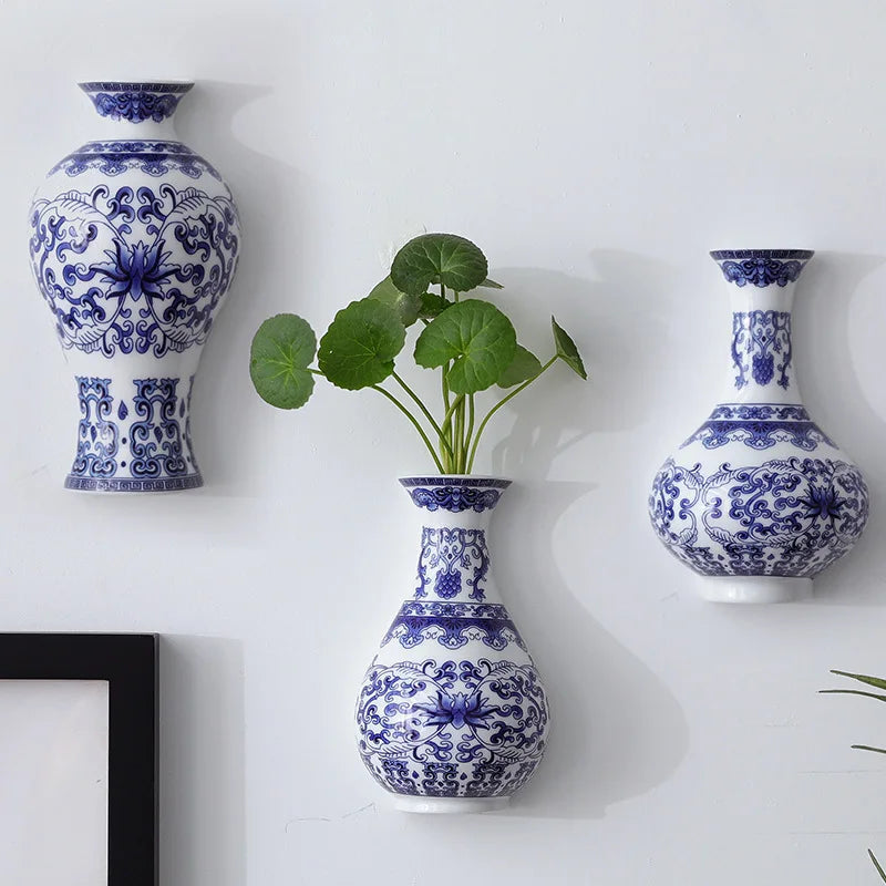 Cette image présente trois magnifiques vases bleu et blanc décorés de motifs floraux élégants, dans lesquels sont disposées des plantes verdoyantes, créant une décoration d'intérieur raffinée et harmonieuse.