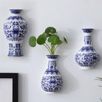 Cette image présente trois magnifiques vases bleu et blanc décorés de motifs floraux élégants, dans lesquels sont disposées des plantes verdoyantes, créant une décoration d'intérieur raffinée et harmonieuse.