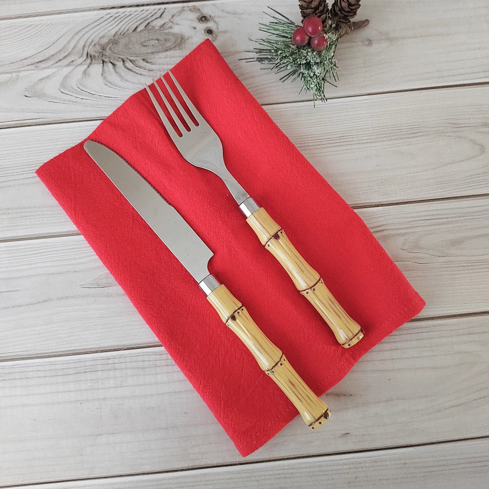 Couverts de cuisine dorés posés sur une serviette rouge sur un fond en bois clair avec une décoration de Noël.