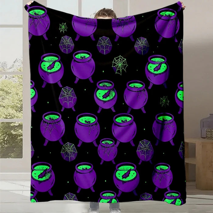 Couverture imprimée de couleurs violette et verte avec des formes de chaudrons et de toiles d'araignée sur fond noir.