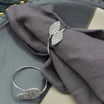 Un élégant anneau en argent orné de cristaux scintillants posé sur un tissu gris foncé.