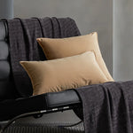 Un fauteuil confortable avec des coussins beiges et une couverture grise, créant une ambiance chaleureuse et apaisante.